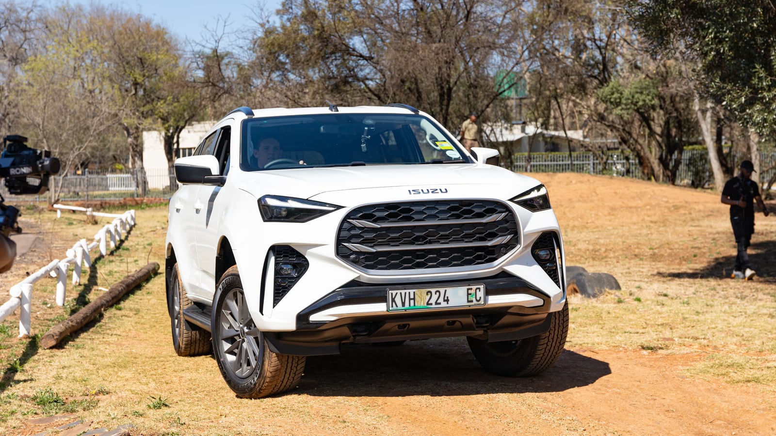 A white Isuzu D-Max X-Rider parked on dry grass under trees