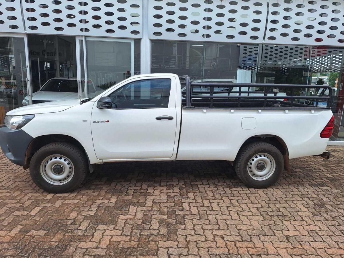 Side view of a white 2021 Toyota Hilux 2.4 GD-6 SR 4x4 single cab with black cattle rails and steel wheels on a Toyota dealer forecourt in Modimolle