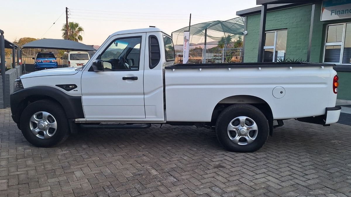 Side view of a white 2022 Mahindra Pik Up S4 4x4 single cab on steel-look wheels, parked on paving at dusk in North West