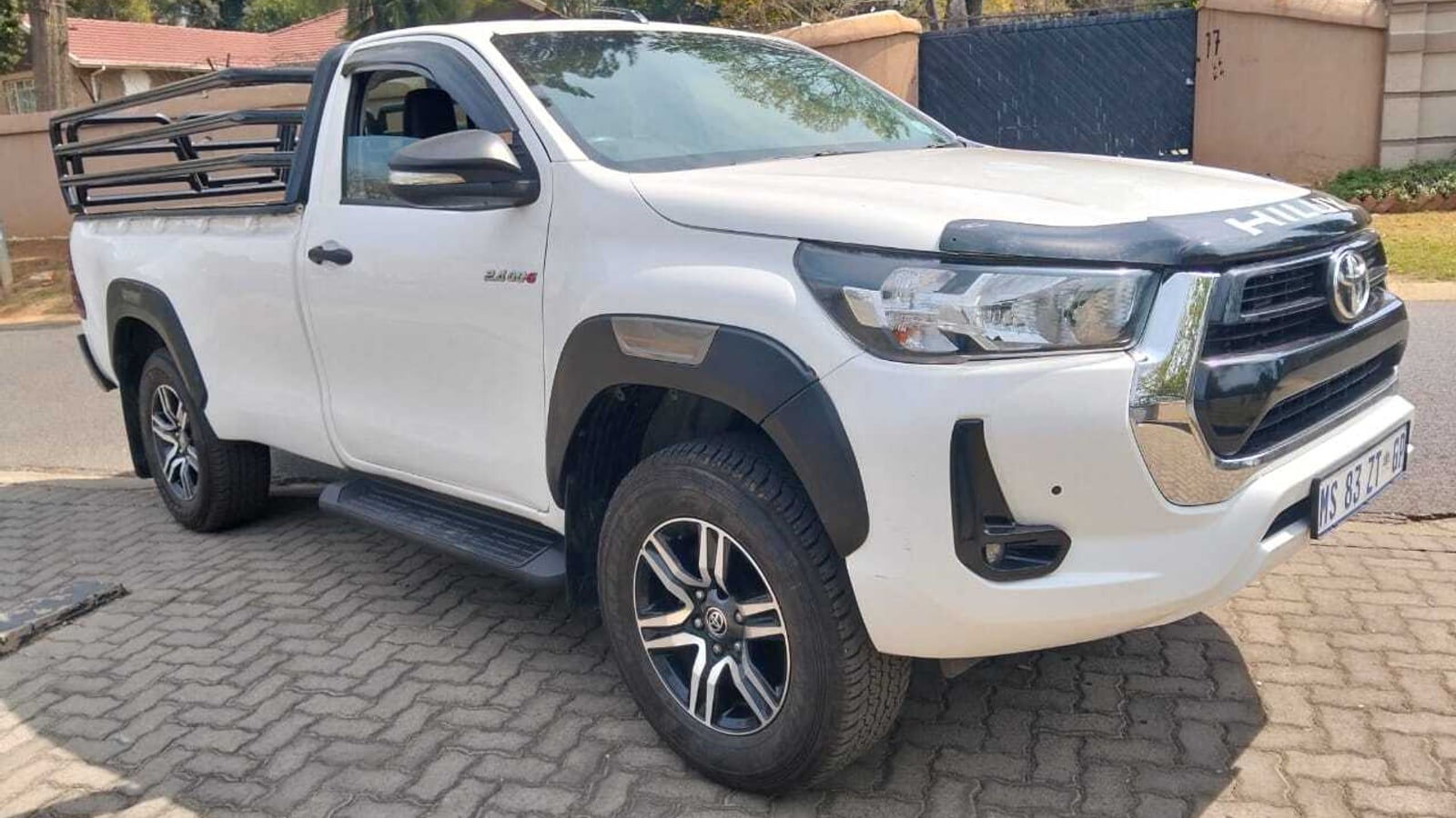 A white 2023 Toyota Hilux 2.4 GD-6 single cab 4x4 with cattle rails on the load bin, parked on a Gauteng street