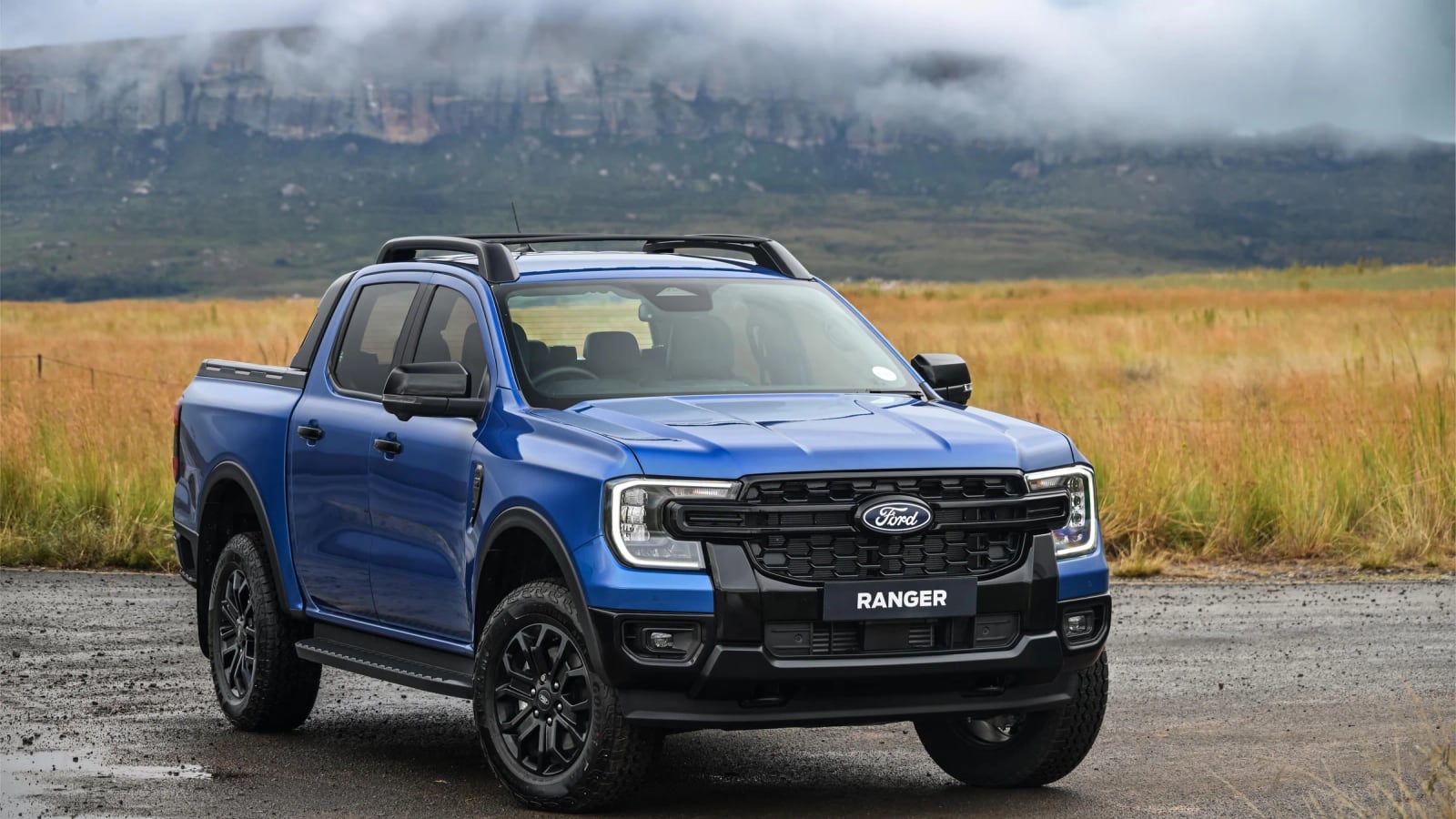 A Ford Ranger double cab on a gravel road in South Africa, dust hanging behind it and open veld to the horizon
