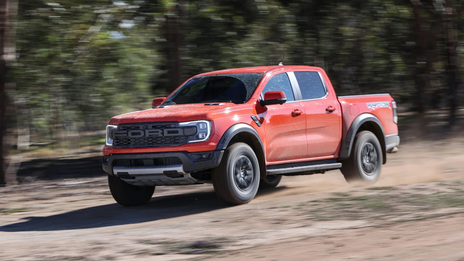 A Ford Ranger Raptor double cab at speed on a gravel track in South Africa, front wheels lifting over a crest