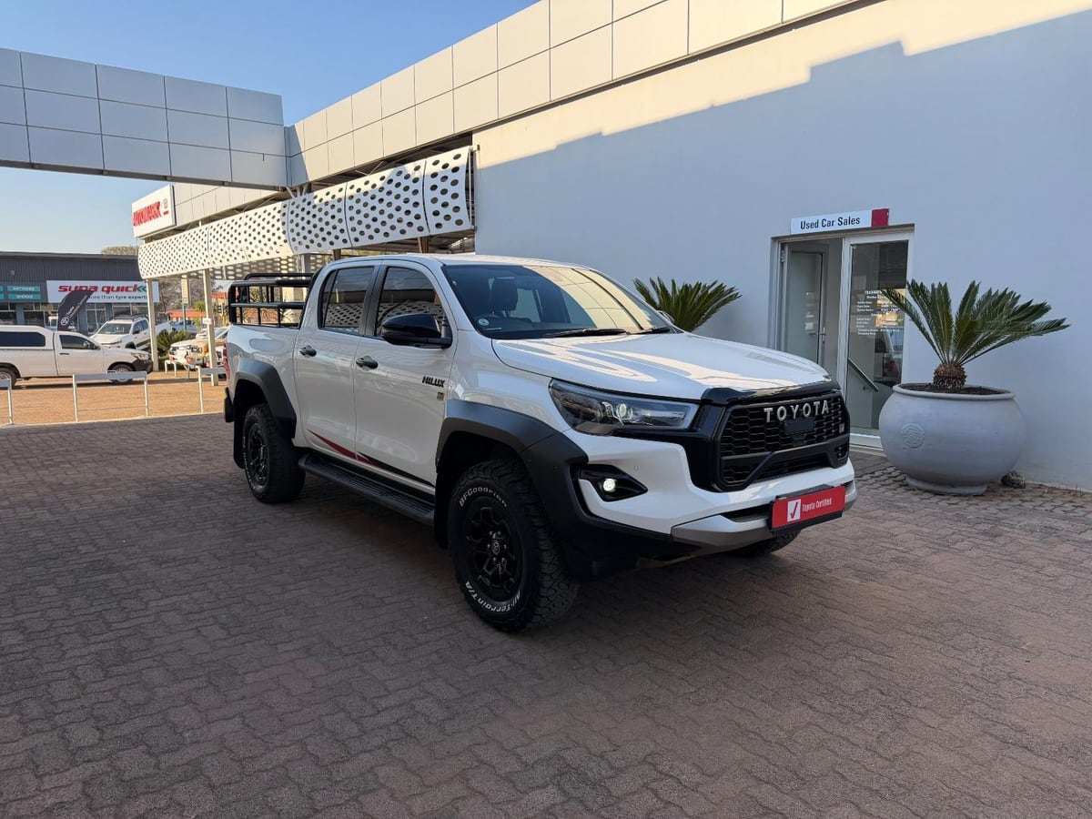 A white 2025 Toyota Hilux 2.8 GD-6 GR-Sport wide-track double cab with black alloys and all-terrain tyres on a brick forecourt at Toyota Modimolle in Limpopo