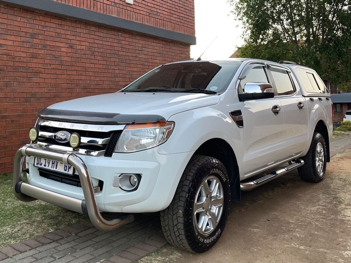 A white 2015 Ford Ranger 3.2 TDCi XLT automatic double cab with a chrome nudge bar, spotlights and a canopy, parked at a face-brick townhouse in Gauteng at dusk