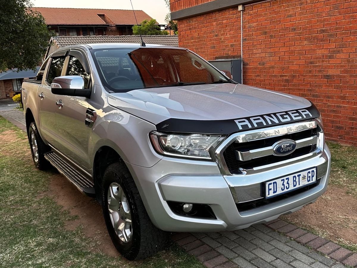 A silver 2016 Ford Ranger 3.2 TDCi XLT automatic double cab with a Ranger bonnet guard, parked on the lawn of a face-brick townhouse complex in Gauteng at golden hour
