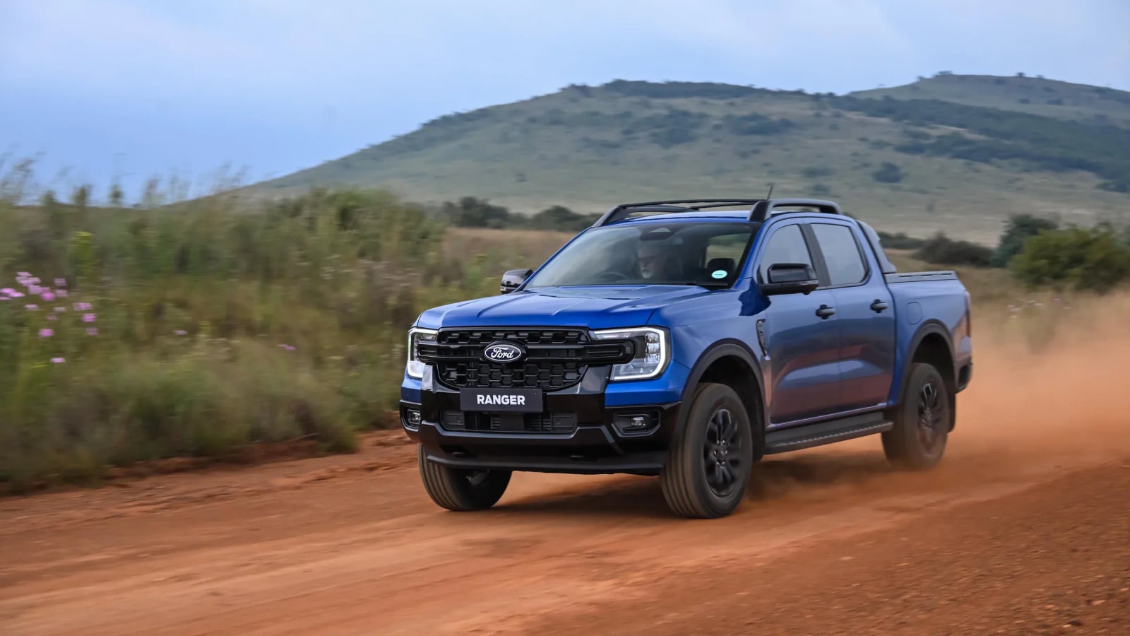 A Ford Ranger kicking up dust on a red gravel road